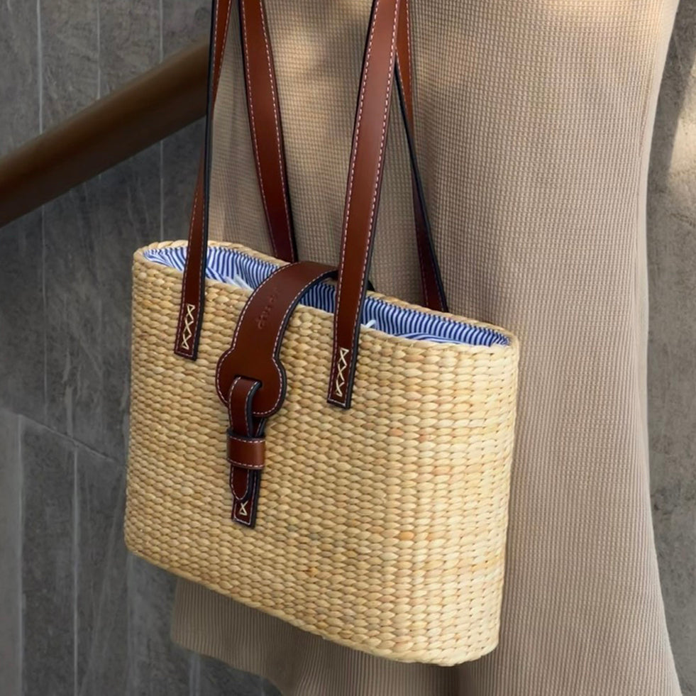 Side angle of the square basket bag showing depth and leather tab fastening