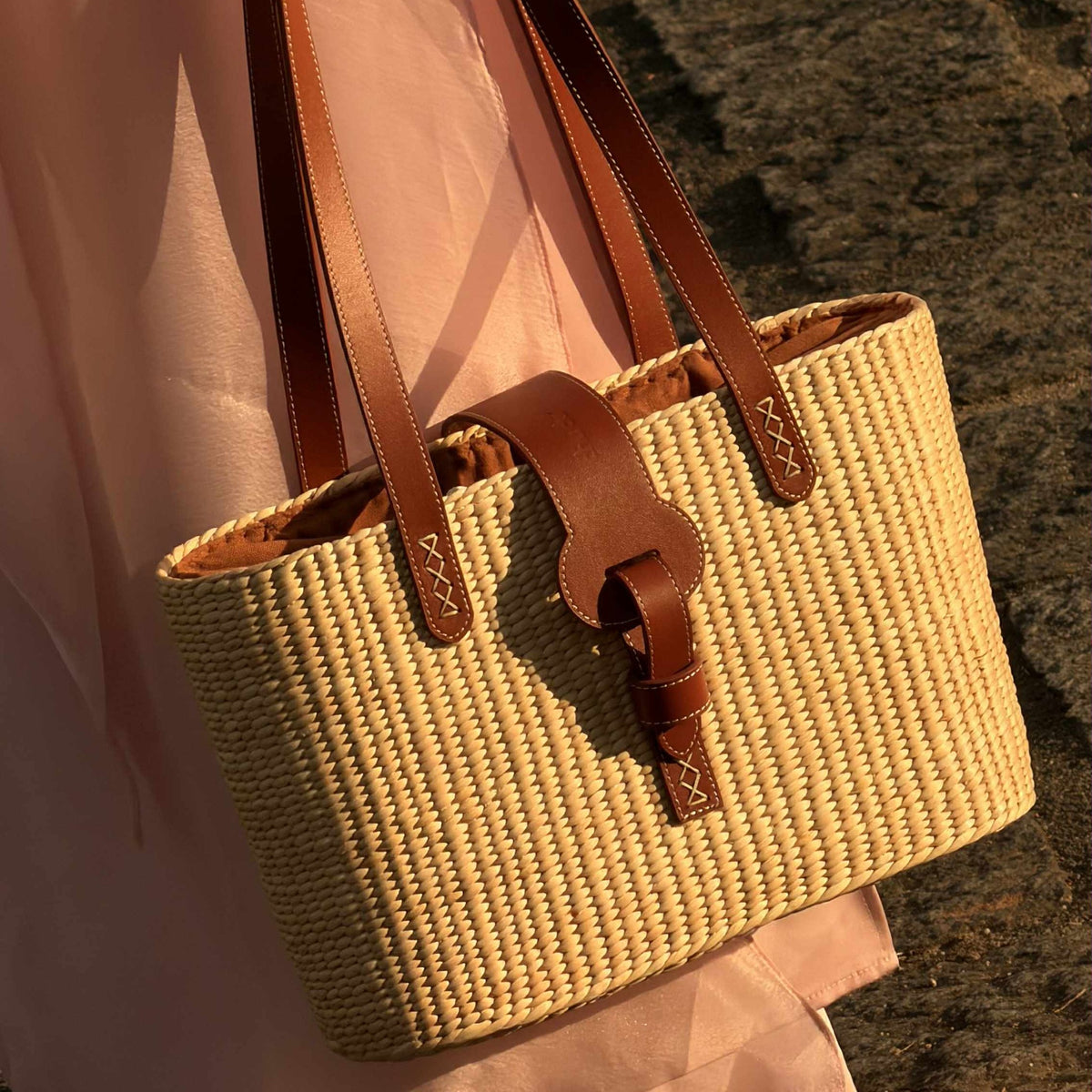 Detail of the leather strap with hand-stitched cross detail on woven straw